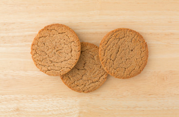 Top view of three brown sugar and cinnamon cookies on a wood table.