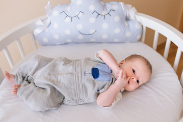 Beautiful newborn baby lying in an round bed with beautiful bumpers in delicate gray, blue, white...