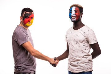 Football fans of Germany and France national teams with painted face shake hands over white background
