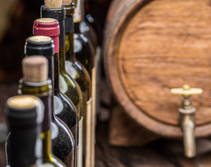 Wine bottles in row and oak wine keg.