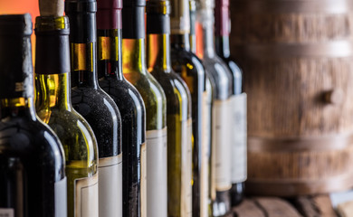 Wine bottles in row and oak wine keg.