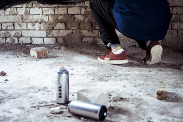spray paint cans near the artist painting on the wall