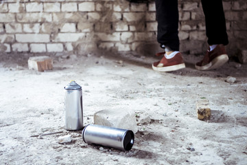spray paint cans near the artist painting on the wall