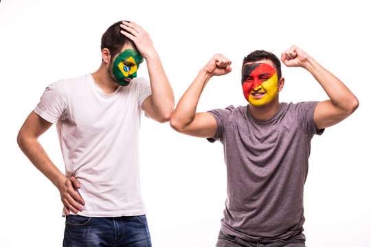 Happy Football fan of Germany celebrate win over upset football fan of Brazil national teams with painted face isolated on white background