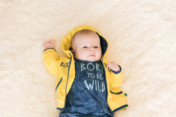 Handsome fashionable little boy lying on a blanket, with a sweet expression