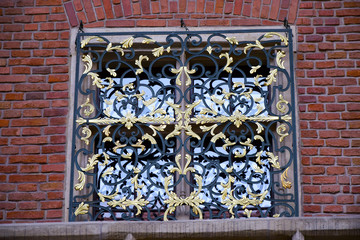 A metallic grid painted in black and gold paint with a reflection of it on the glass. Texture and...