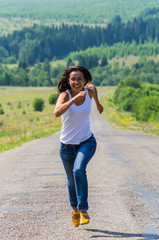 cheerful girl runs along the highway towards
