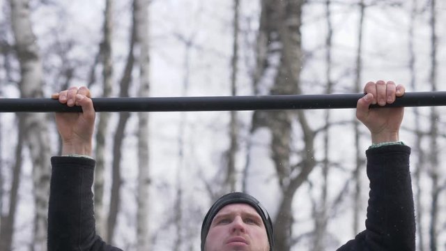 Bearded man doing pull up exercise during outdoor training on sport ground
