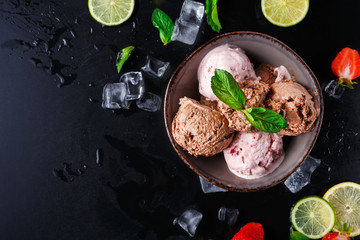 Portion of ice cream scoops with fruit on black