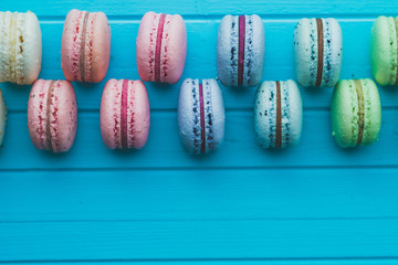 Cookies macaron or macaroons lie on a wooden turquoise background in checkerboard pattern, top view close-up, copy space