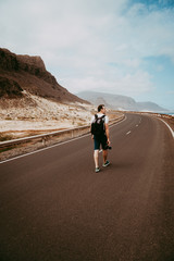 Traveler walks in the center of an epic winding road. Huge volcanic mountains in the distance behind him. Sao Vicente Cape Verde