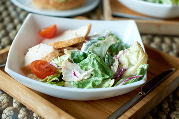 Caesar salad is on the plate in a restaurant.