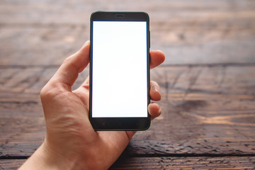 mens hand holding smartphone with blank screen for your logo or design on dark wooden table