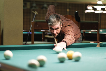 a pool player takes aim at the ball