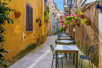 Cafe tables and chairs outside in old cozy street in the Positano town, Italy