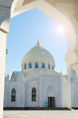 Fototapeta na wymiar White mosque. View through the arch, sunlight