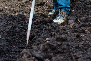 Man digging trench in soil with hoe