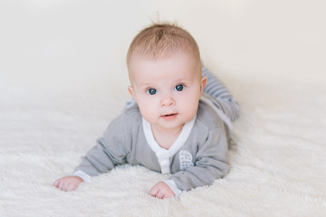 Small baby boy lying on stomach and raising his head awhile looking surprised and smiling cute, newborn