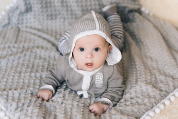 Small baby boy lying on stomach and raising his head awhile looking surprised and smiling cute, newborn