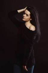 Model test with lovely brunette model in knitted sweater posing over a black studio background
