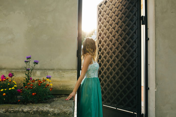 Stunning blonde model with wavy hair wearing lace dress, posing in sun rays in the morning