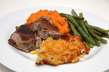 gigot with swiss hash browns, mashed carrots and beans