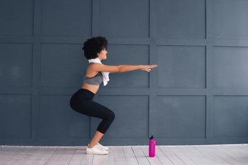 Commit to be fit! Good-looking gorgeous young lady doing sport with a white towel on her neck and modern water bottle in front.