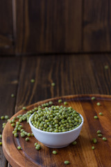 Organic mung beans on white ceramic bowl over wooden background.