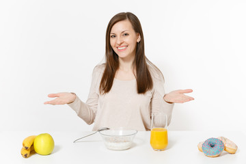 Young woman sitting at table breakfast with cereals and milk, orange juice in glass, donuts isolated on white background. Proper nutrition, delicious tasty food, healthy lifestyle. Area to copy space.