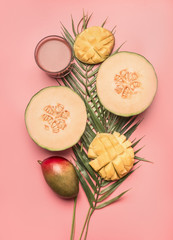 concept of a vegetarian, healthy food, fresh sliced mango and melon with smoothies, space for text, pink background flat lay