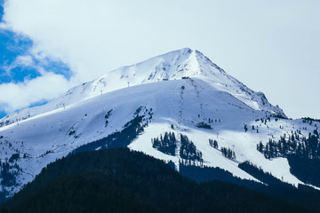 Mountain snow peak, beautiful natural winter backdrop. Ice top of the hill, blue sky background. Alpine landscape.