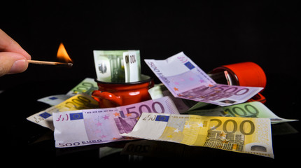 Burning euro banknotes. Euro reflection on a black surface
