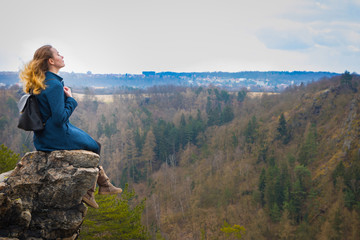 Naklejka na ściany i meble The girl sitting on the rock in mountain, relaxing in nature