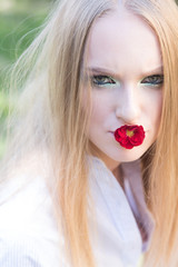 Womens day, 8 march, spring concept. Woman with red flower in mouth, 8 march. Fashion model with long blond hair, hairstyle on nature. Beauty girl with glamour look, makeup.