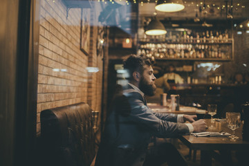 Bearded man rest in restaurant with beer glass. serious bar customer sit in cafe drinking ale. Date meeting of hipster awaiting in pub. Beer time. Businessman with long beard drink in cigar club.