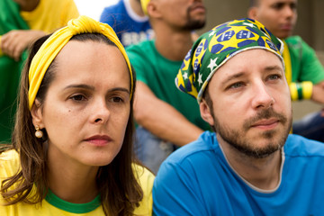 Group of fans watching a match and cheering brazilian team.