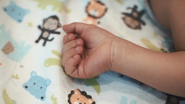 little girl opens a tiny palm lying on her back on the children sheet