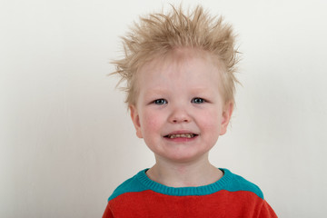 Naklejka premium Happy Caucasian blonde with microphone. Drummer play on a new drum kit. Parents bought a drum box for training. Child in bright clothes with new chopsticks in hands happy at home. Bright emotions