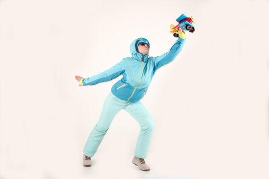 Slender young girl in blue ski suit with toy airplane in her hands posing for sculptor. The concept of sport lifestyle. Busy schedule of young business woman. Collection of sportswear. Pilot style