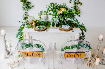 Wedding Banquet. Armchairs and table for newlyweds, served with cutlery and tableware with festive decorations.