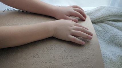people with disabilities, blind child reading book of characters font close-up