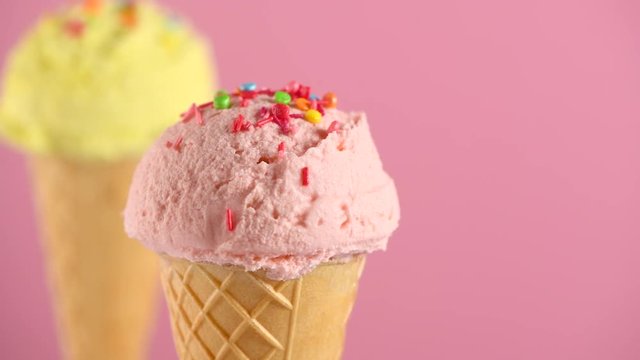 Ice cream. Various icecream scoops in waffle cones rotated on pink background. Strawberry or raspberry, banana or lemon flavors. Sweet dessert closeup. 4K UHD video footage. 3840X2160