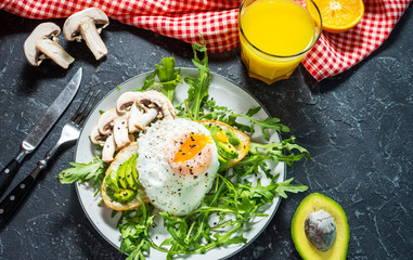 Tasty sandwiches with avocado and egg, arugula on black stone background. Delicious breakfast