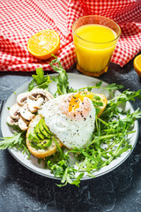 Tasty sandwich with avocado and egg, arugula on black stone background. Delicious breakfast