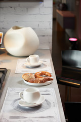 Delicious croissant and a two cup of coffee on a kitchen counter. Healthy breakfast with coffee in sunny morning for two person in modern kitchen interior