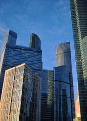 Low angle view of skyscrapers against blue cloudy sky. City landscape. Sunset.	