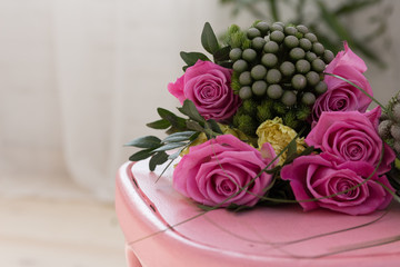 Bunch of pink roses lying on pink shabby chic style wooden chair decorated with decoupage technique