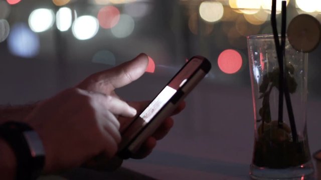 Man browsing photos on smartphone at night
