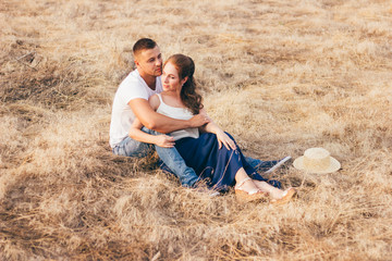 Beautiful guy and girl holding hands, kissing. Love story photo on outdoor in sunset light. Models. Couple in love. Pretty girl and brutal guy walking in outdoor. Shallow focus and some noise.