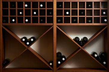 Bottles of white and red wine on a wooden shelf with books in private winery cabinet room interior 